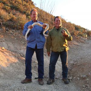 Marc and jeff holding animals outside.